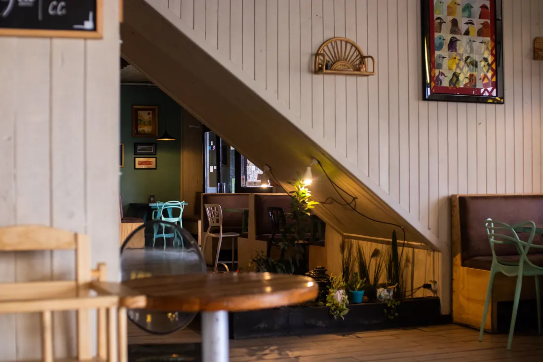 Interior de cafetería con madera y plantas (imagen ilustrativa, no es el local)